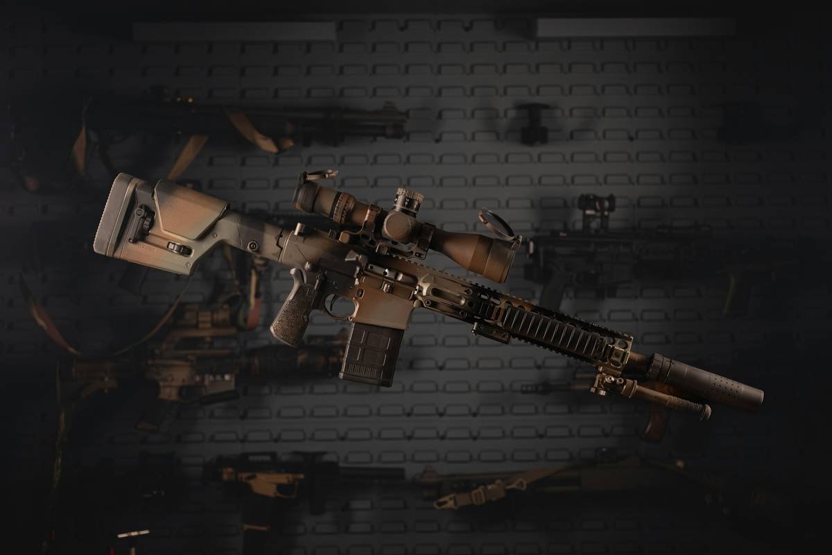 A rifle with scope and attachments is displayed.