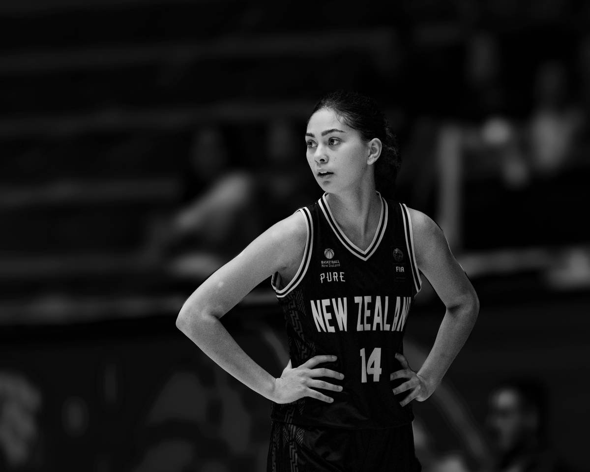A woman standing on a basketball court with her hands on her hips
