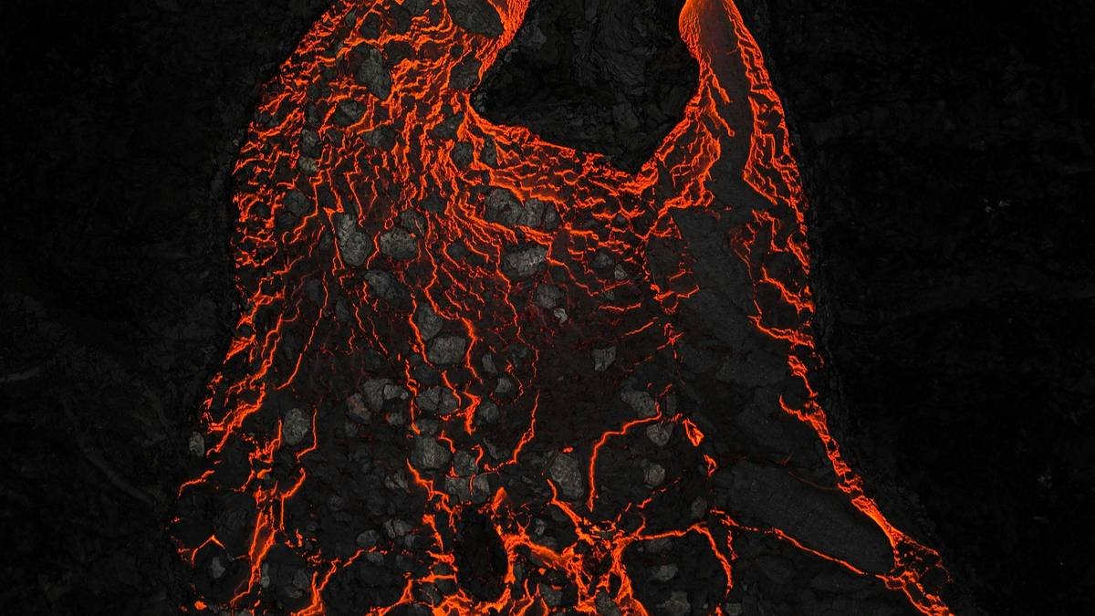 Molten lava flowing in darkness with glowing red patterns